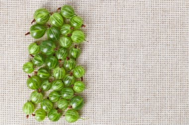 Many gooseberry fruits on gray linen table cloth with copy space