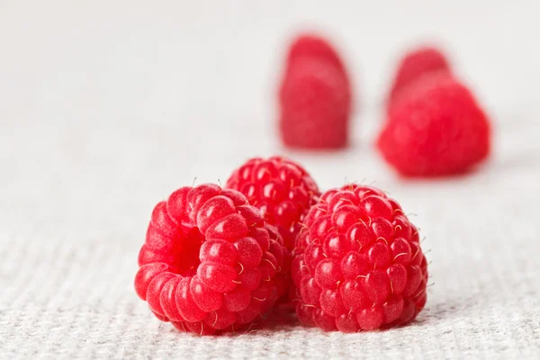 Still life with three red raspberry on gray linen table cloth, c — Stock Photo, Image