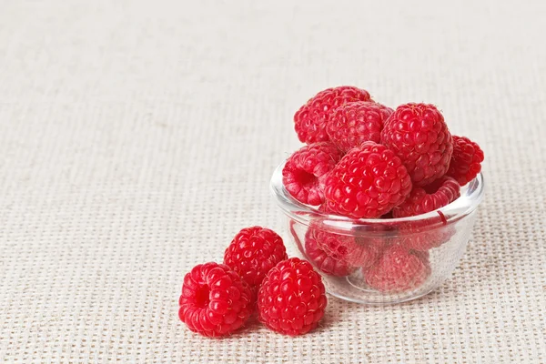 Still life with red raspberry and glass bowl on gray linen table — Stock Photo, Image