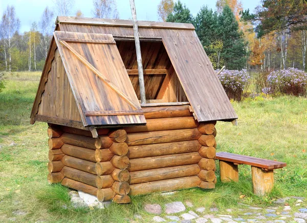 Dřevěné studny stylizovaná, semi-starožitné proti venkovské krajiny — Stock fotografie