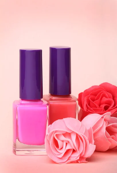 Nagellackflaschen und Rosenblüten — Stockfoto