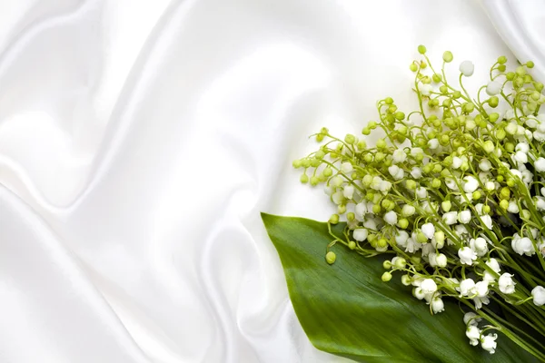 Lily of the valley on white silk background — Stock Photo, Image