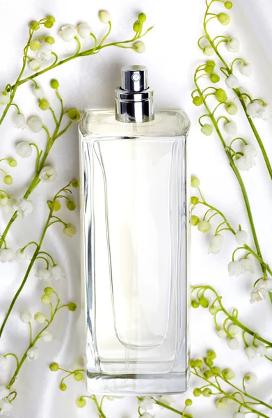 Konwalia i butelki perfum na biały jedwab — Zdjęcie stockowe