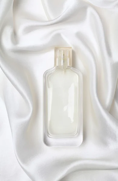 Witte parfumfles op de zijde. — Stockfoto