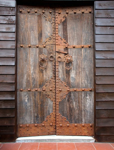 Large wooden door with bronze fittings and lion shaped door knockers