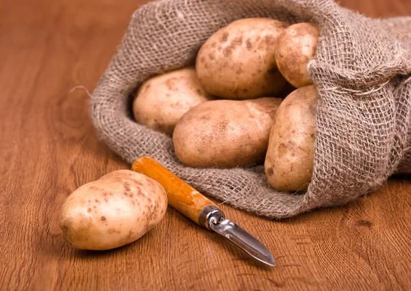Aardappelen met mes om de groenten op de natuurlijke backg schoon te maken — Stockfoto