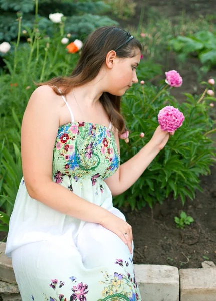 Girl against pink peony flowers — Stock Photo, Image