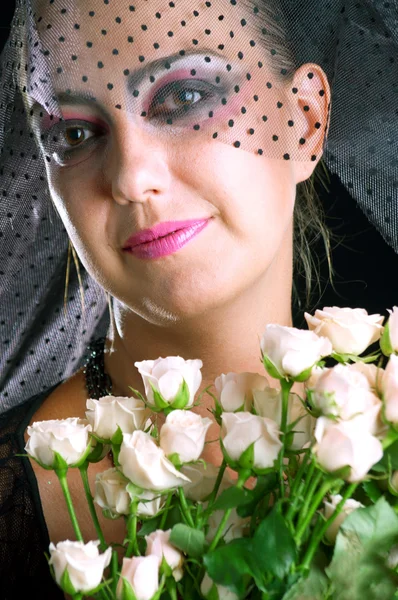 Meisje in een zwarte sluier met roze rozen — Stockfoto