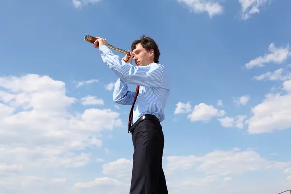 Young business man looks through a telescope — Stock Photo, Image