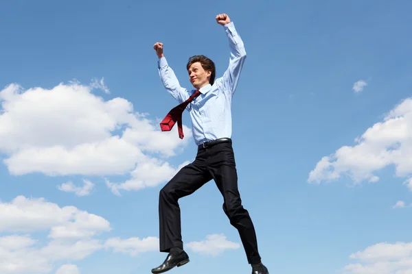 Jumping young businessman in a blue shirt — Stock Photo, Image