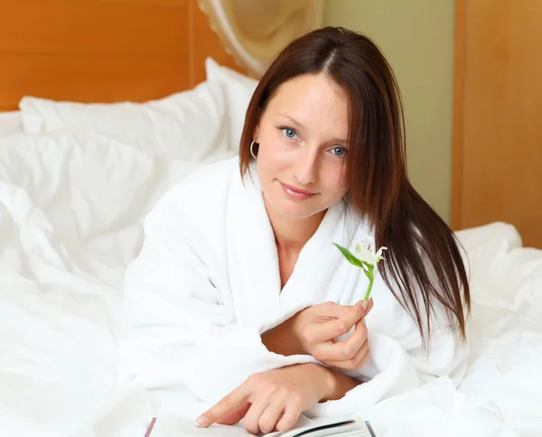 Mujer joven en la cama leyendo un libro —  Fotos de Stock