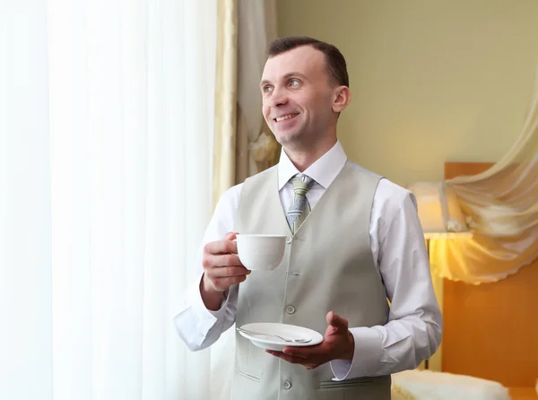 Молодой бизнесмен у окна пьет чай — стоковое фото