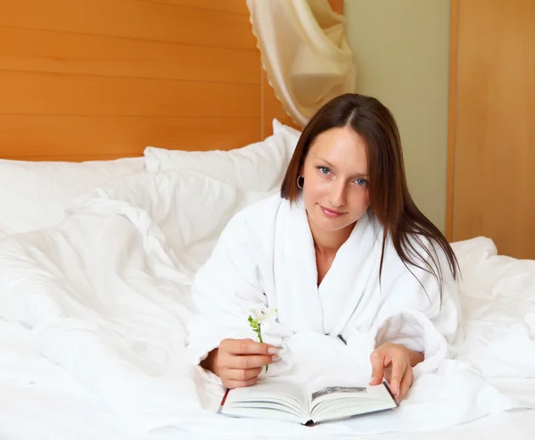 Ung kvinna i sängen läsa en bok — Stockfoto