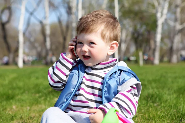 Маленький мальчик с мобильным телефоном в парке — стоковое фото