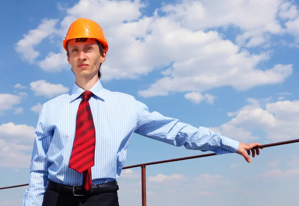 Молодой инженер в синей рубашке и желтом шлеме — стоковое фото