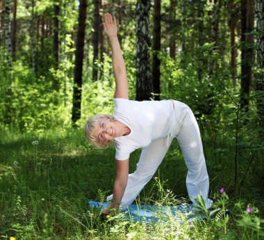 Yaşlı bir kadın yoga yapıyor.