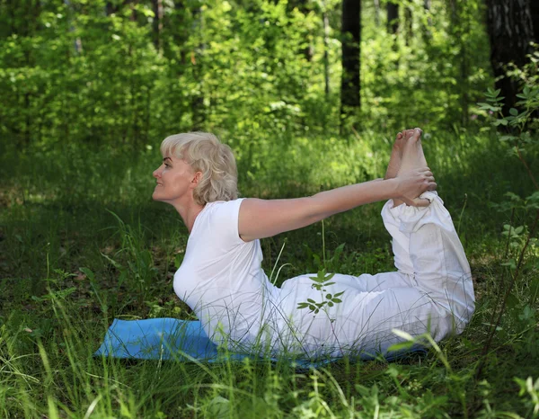 Yaşlı bir kadın yoga yapıyor. — Stok fotoğraf