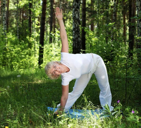En äldre kvinna utövar yoga — Stockfoto