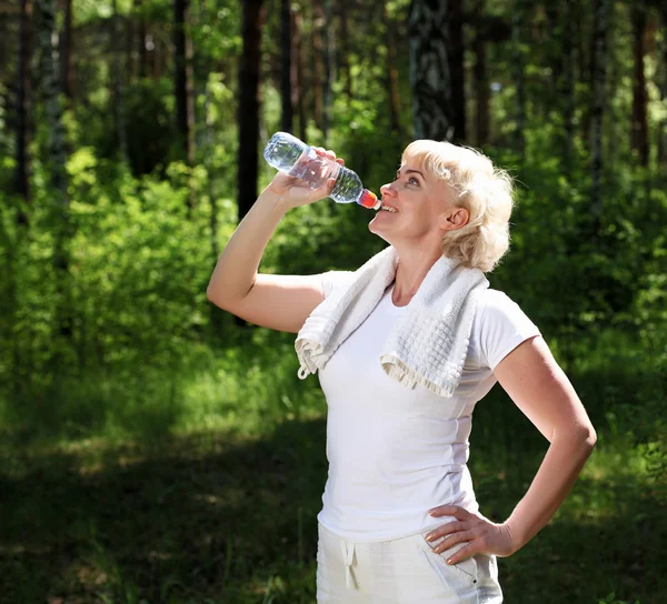 Elderly woman after exercising in the forest — Stock Photo, Image