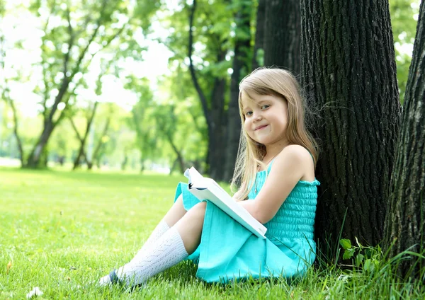 Портрет маленької дівчинки, що читає книгу в парку — стокове фото