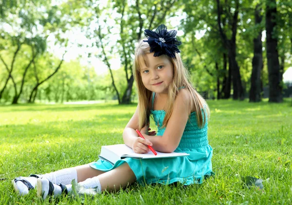 Küçük kız parkta bir kitap okuma portresi — Stok fotoğraf