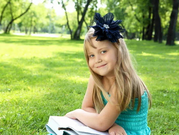 Portrait of little girl reading a book in the park — Stock Photo, Image