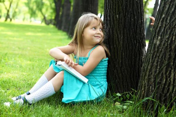 Ritratto di bambina che legge un libro nel parco — Foto Stock