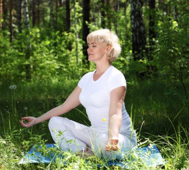 Yaşlı bir kadın yoga yapıyor.