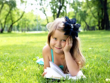 küçük kız parkta bir kitap okuma portresi