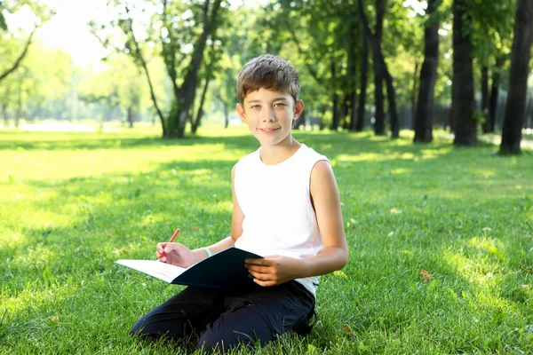 一个男孩拿着一本书在公园里的肖像 — 图库照片