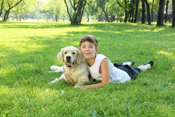 Мальчик-теннисист в парке с собакой — стоковое фото
