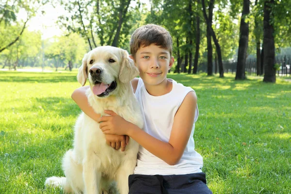 Tennager boy in the park with a dog — Stock Photo, Image