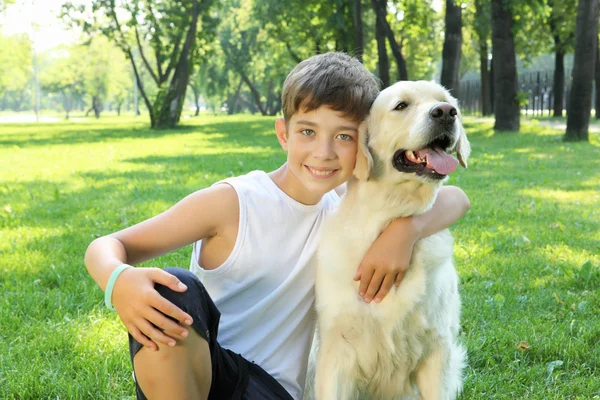 Tennager jongen in het park met een hond — Stockfoto