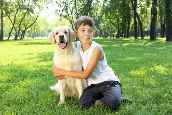 Tennager boy in the park with a dog — Stock Photo, Image
