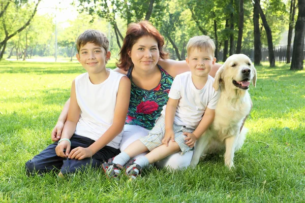 Mãe e seus dois filhos no parque com um cão — Fotografia de Stock