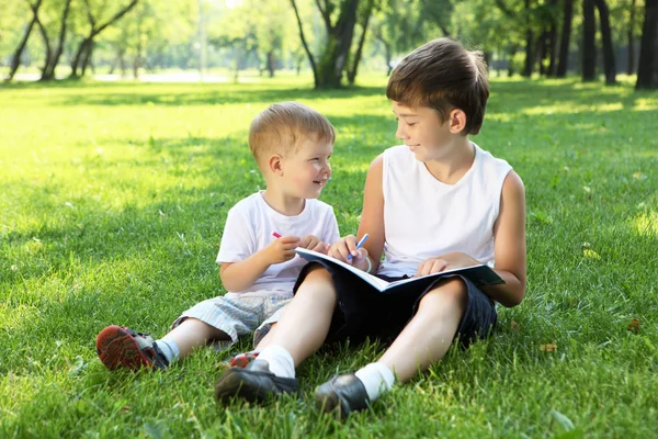 Τα παιδιά στο πάρκο διαβάζοντας ένα βιβλίο — Φωτογραφία Αρχείου