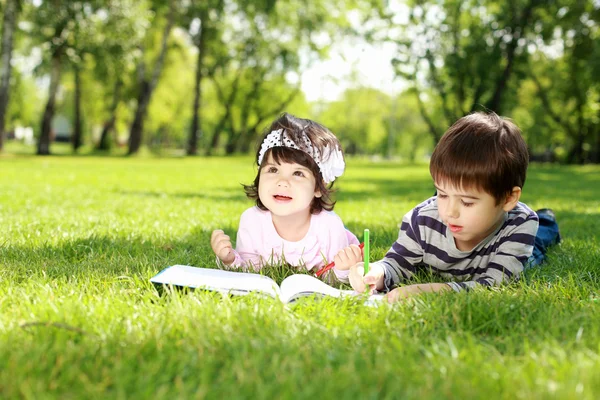 Crianças no parque lendo um livro — Fotografia de Stock