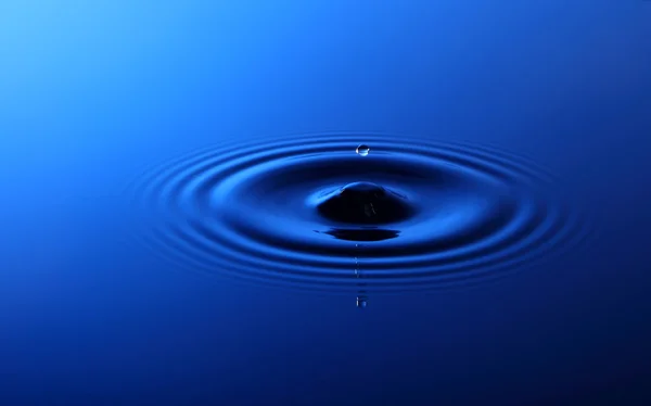 Drop of water falling into the water — Stock Photo, Image