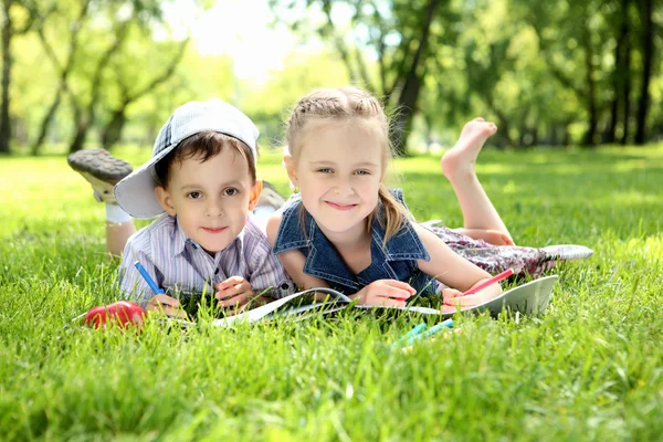 Crianças no parque lendo um livro — Fotografia de Stock