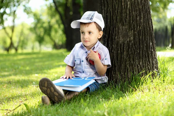 Retrato de un niño con un libro en el parque — Foto de Stock