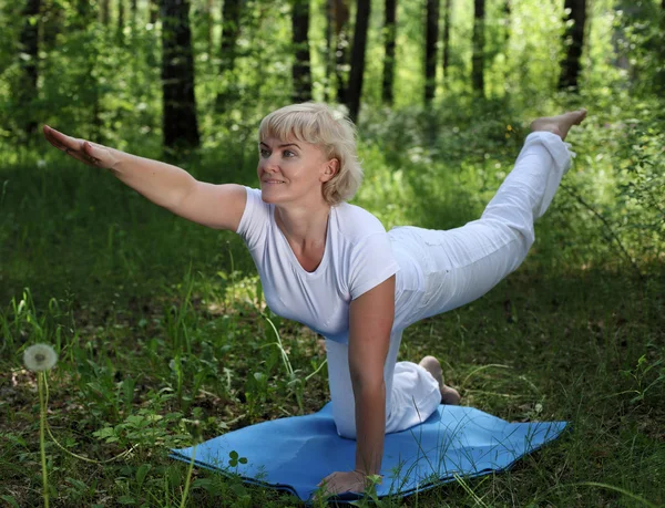 Yaşlı bir kadın yoga yapıyor. — Stok fotoğraf