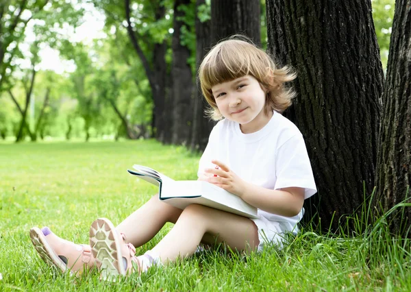 Портрет маленькой девочки, читающей книгу в парке — стоковое фото