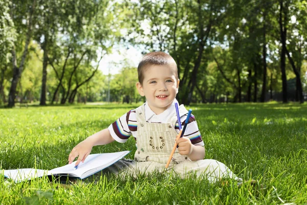 Retrato de un niño con un libro en el parque —  Fotos de Stock