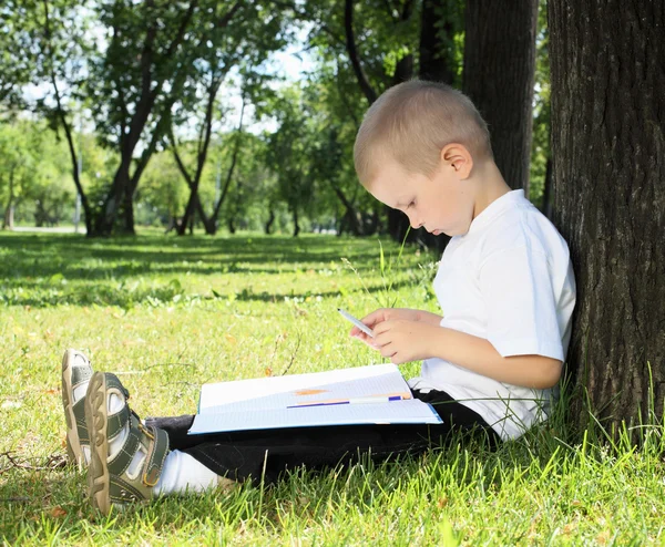 Portréja egy fiú egy könyvet a parkban — Stock Fotó