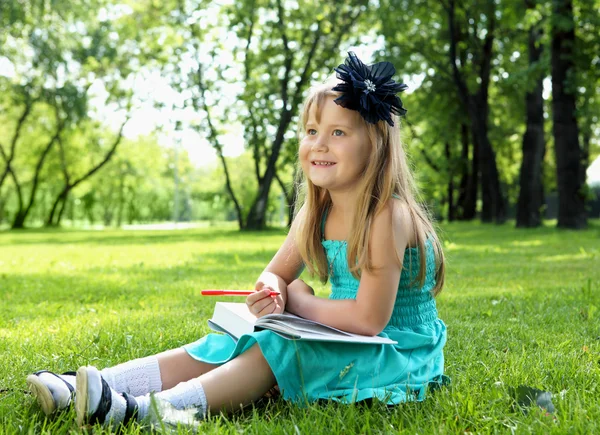 Portret van meisje het lezen van een boek in het park — Stockfoto