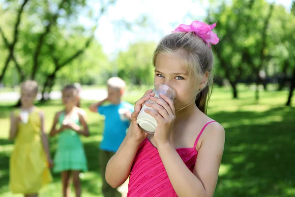 Девушка пьет молоко в летнем парке — стоковое фото