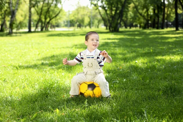 Malý chlapec v parku hrát s míčem — Stock fotografie