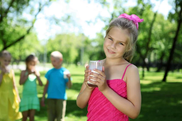 Chica bebiendo leche en el parque de verano — Foto de Stock