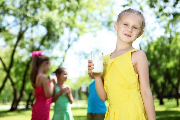 Meisje consumptiemelk in de zomer park — Stockfoto