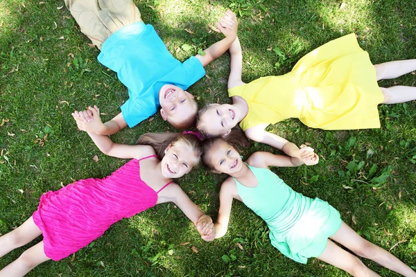Дети, лежащие на траве в летнем парке — стоковое фото